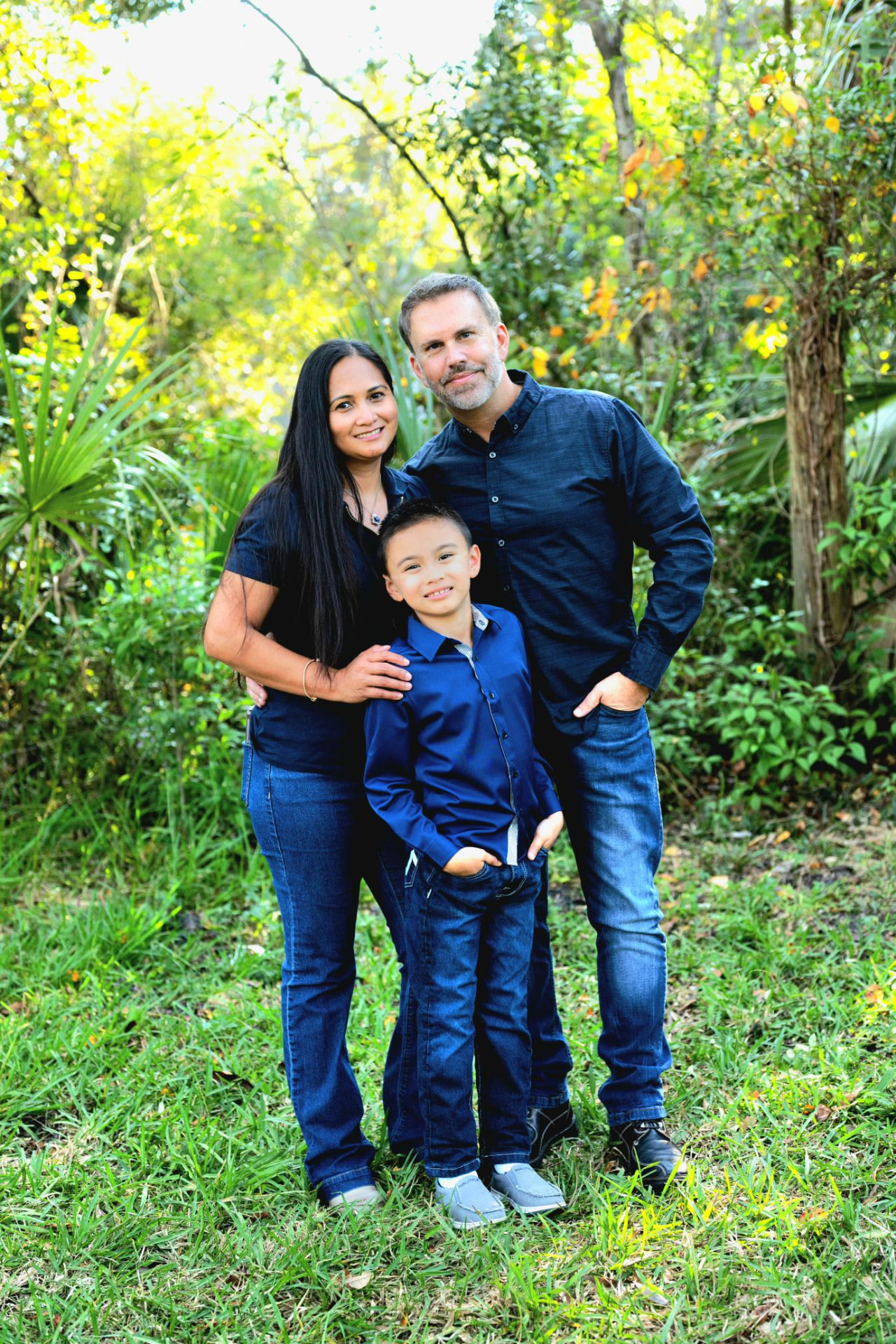 Rich, Jenny, and Ethan Bussey smiling together in a sunny green garden